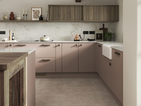 Modern kitchen showroom display with pink cabinetry, marble backsplash, and wood accents.
