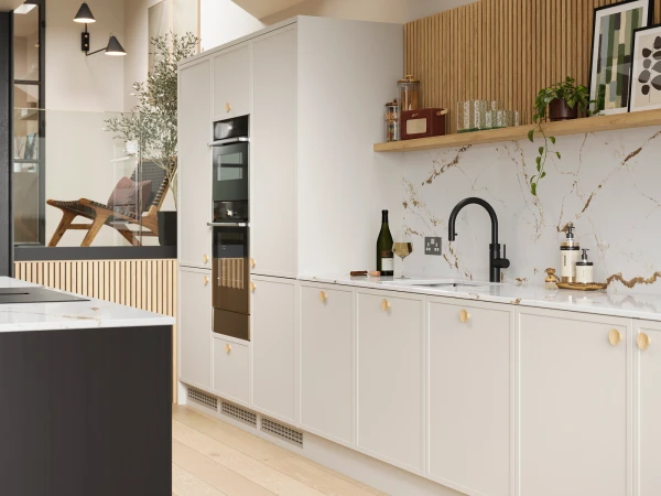 Modern kitchen with white cabinetry, marble countertops and backsplash, black tap and built-in appliances, wooden open shelving with accessories and plants, wood slat accent wall, pendant lights, and view into adjoining room with mid-century chair through glass partition.